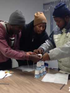 Landforce Crew Members stacking six cups using string and a rubber band.